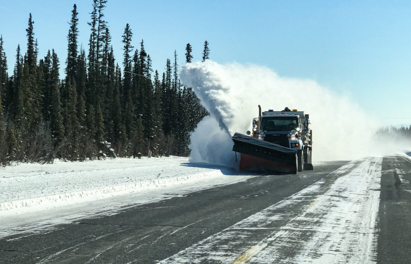 Snow plow clearing snow from a mountain road